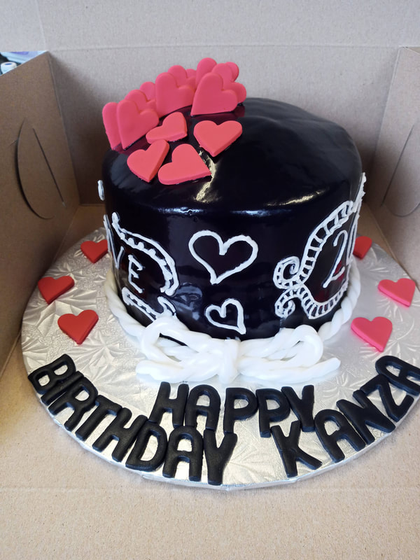 Black birthday cake with white decorations and red hearts