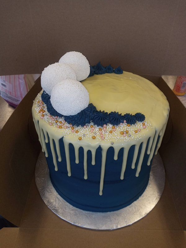 Navy Blue cake with yellow drip icing and navy, white and gold decorations