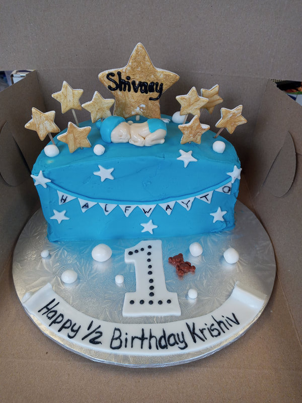 Half birthday cake with gold stars and sleeping baby