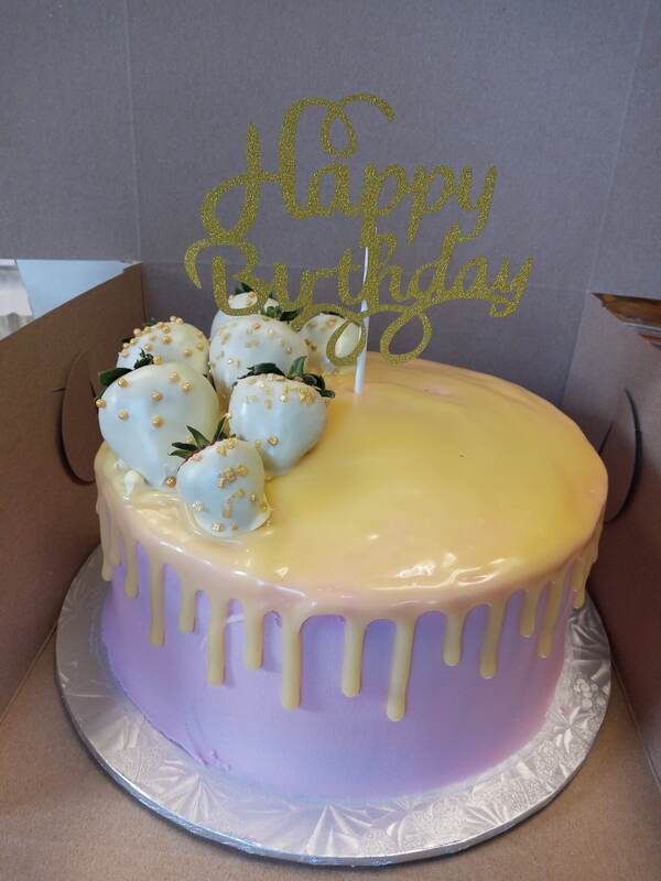 Pink cake with yellow drip icing and white chocolate dipped strawberries