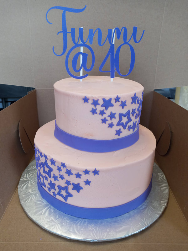 White 40th birthday cake with blue ribbons around the base and blue stars