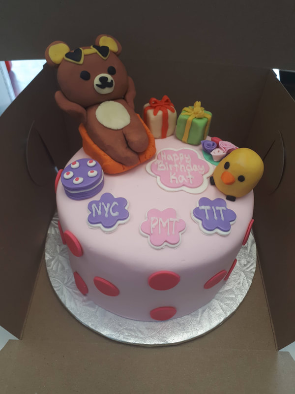 Light pink birthday cake with red polka dots, a lounging bear, a yellow bird, present, a cake and flowers