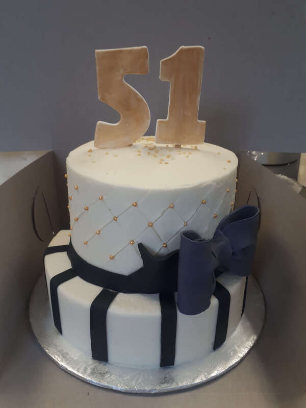 Two tiered white cake with black and gold decorations