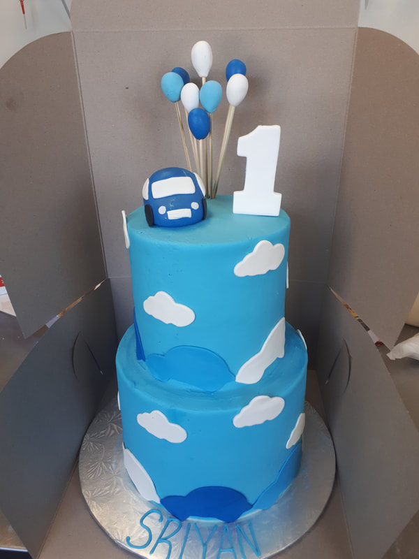 Blue cake with clouds, a car and balloons
