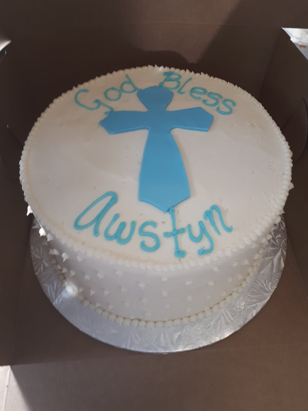 White communion cake with blue cross and writing