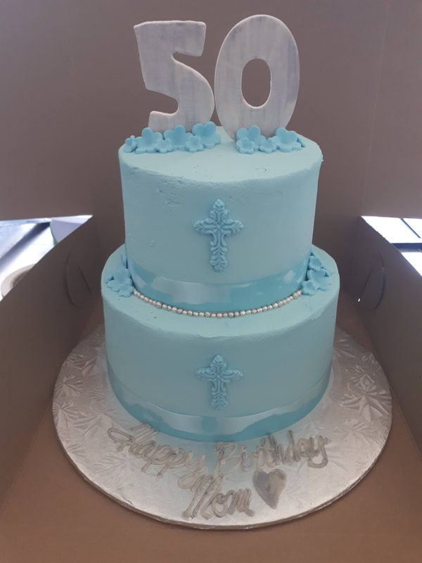 Two tier baby blue cake with flowers and crosses