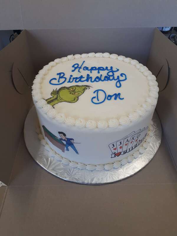 White birthday cake with pictures of the Grinch, a man playing pool and cards