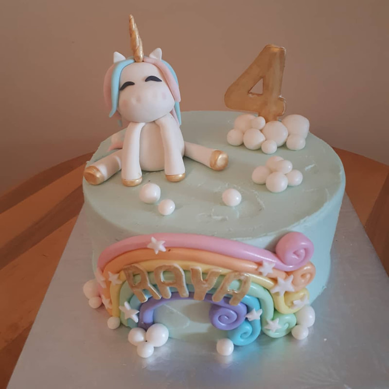 Cake with unicorn on top and a rainbow on the side